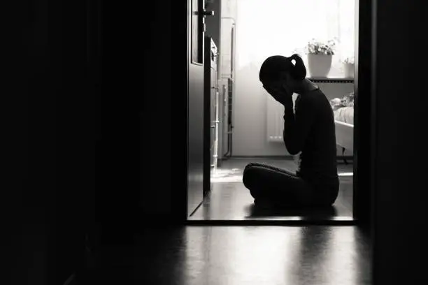 Young woman sitting on floor expressing sad feelings and emotions