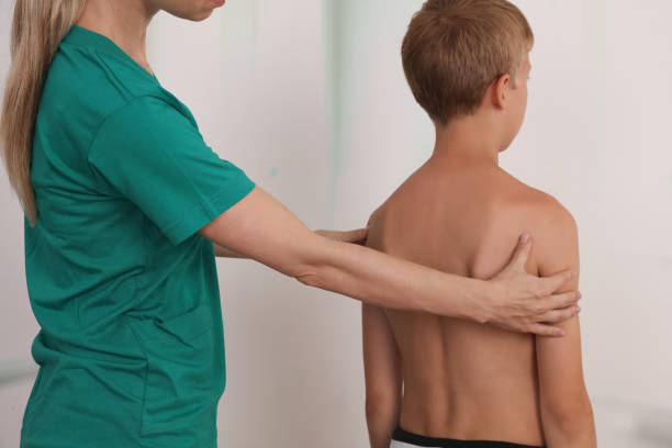 istock Child having chiropractic back adjustment. Osteopathy, Physiotherapy, Kinesiology. Bad posture correction 1158890345