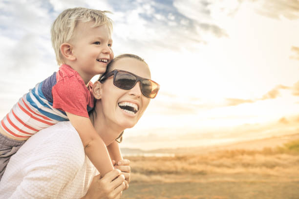 Happy mother having fun with her son at sunset