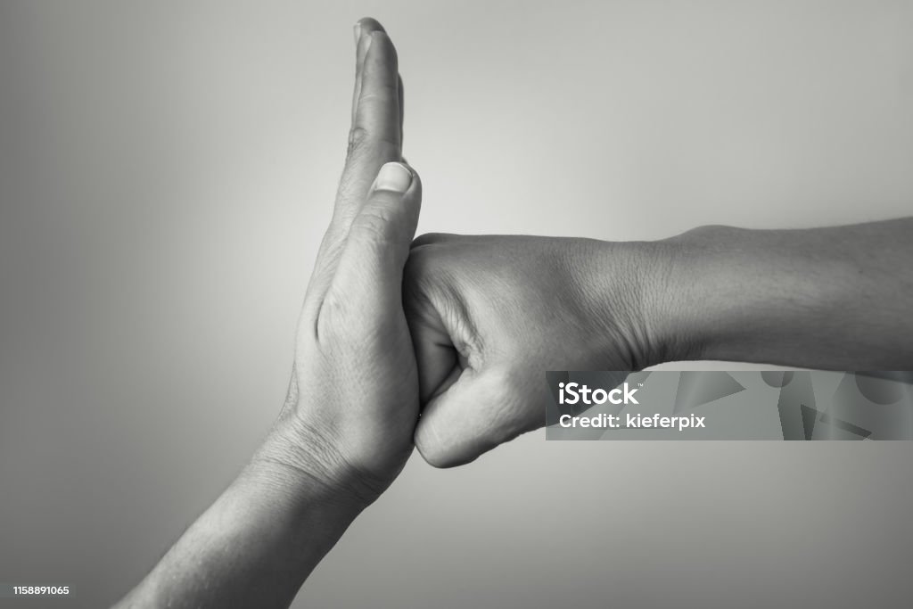 Stop! Hand preventing stopping punch attack of another hand. Violence Stock Photo
