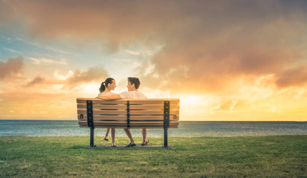 Affectionate mature couple sitting on a bench in park during autumn