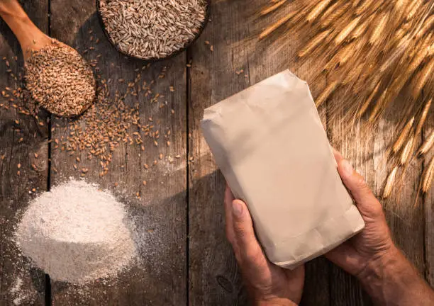 High angle view of male hands holding organic handmade einkorn flour over wooden table