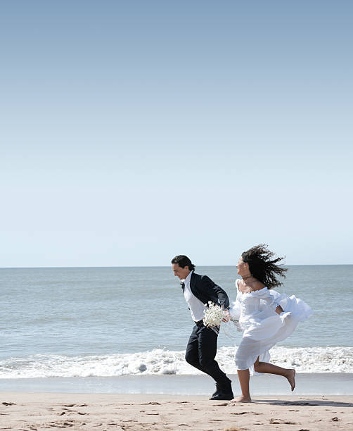 istock Bride and groom running at the beach 115889195