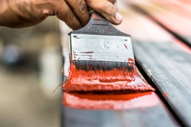 a professional man is painting red color by a bush