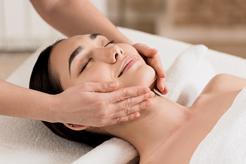 woman getting face massage with closed eyes at spa