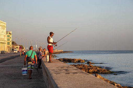 Havana, Cuba - May 14, 2019: Cuban people are fishing in the ocean early morning during a sunny sunrise, taken during the Shortage of Food Crisis.