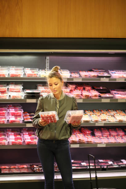 mujer comprando un paquete de carne en el supermercado - supermarket meat women packaging fotografías e imágenes de stock