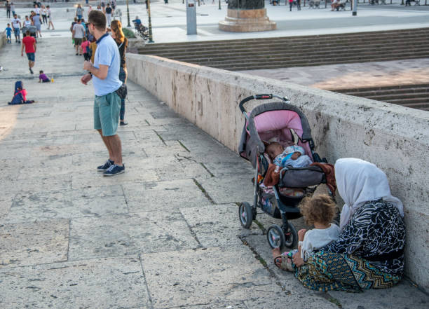 SKOPJE,MACEDONIA-AUGUST 29,2018:Albanian Roma woman and children beg for money,sitting along Stone Bridge,next to Macedonia square,Skopje.
