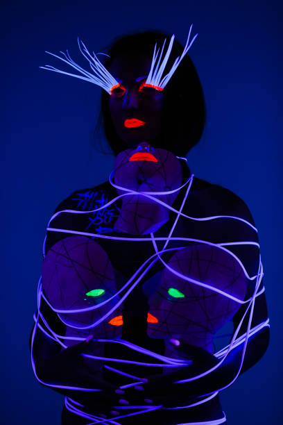 istock One woman painted with fluorescent make up holding abstract masks. 1158912748