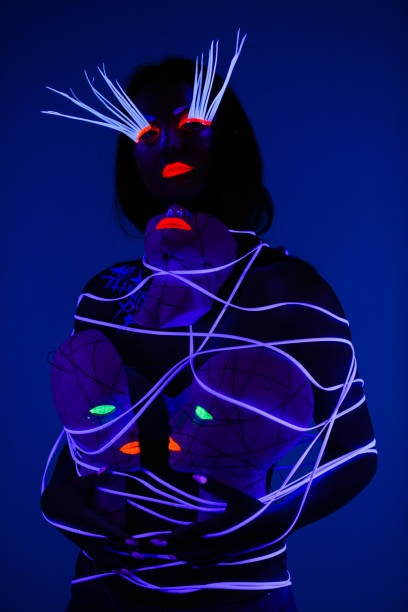 istock One woman painted with fluorescent make up holding abstract masks. 1158912753