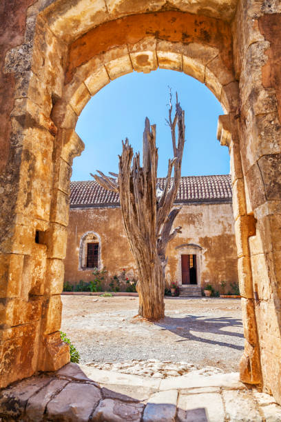 Dried tree behind the arch of old monastery . Arkadi monastery - Crete, Greece.