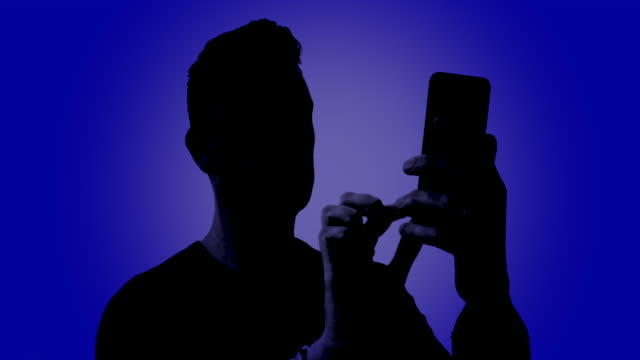 Silhouette of a male using his smartphone on a digital blue background
