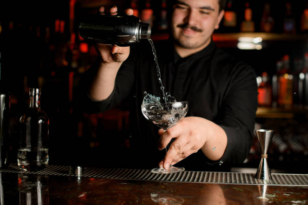 istock Bartender pouring an alcohol from shaker to glass 1158970069