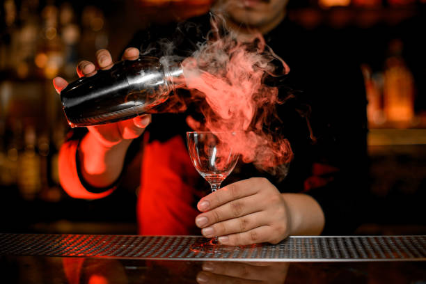 istock Bartender pouring steamy cocktail from shaker to glass 1158970106