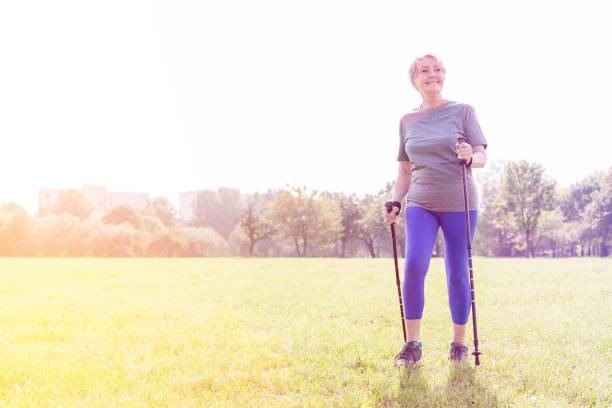 istock Smiling senior woman using trekking poles while walking in park 1158970711