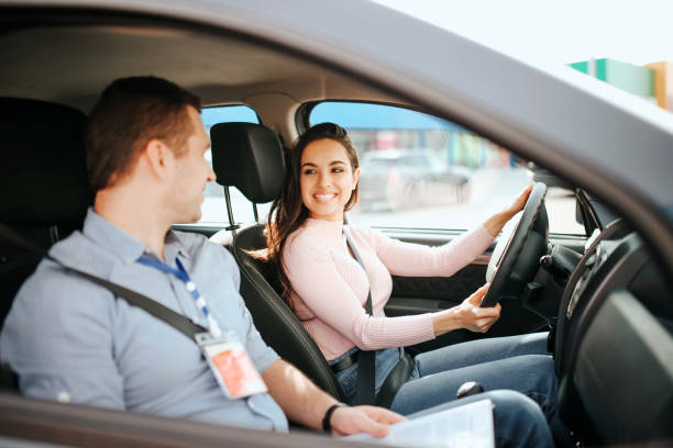 l'istruttore di auto maschile fa esame in giovane donna. allegro modello attraente e positivo guardare ragazzo e sorriso. guida l'auto con sicurezza. - driving test foto e immagini stock