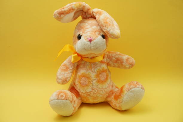 istock cute easter bunny rabbit plush doll Sitting on yellow background 1158973300