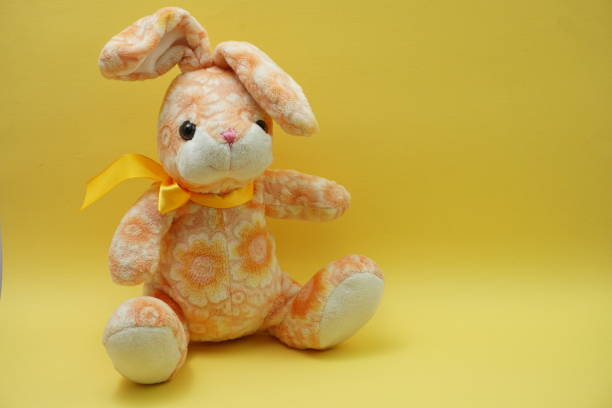 istock cute easter bunny rabbit plush doll Sitting on yellow background 1158973315