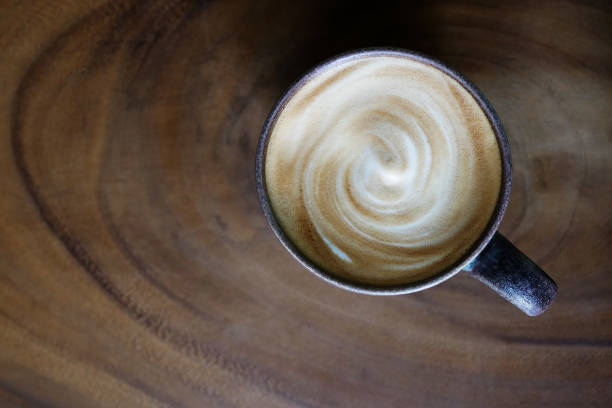 widok z góry gorącej kawy cappuccino latte cup z mieszaną spiralną pianką mleczną na tle stołu z teksturą drewna. - cappuccino swirl coffee cafe zdjęcia i obrazy z banku zdjęć