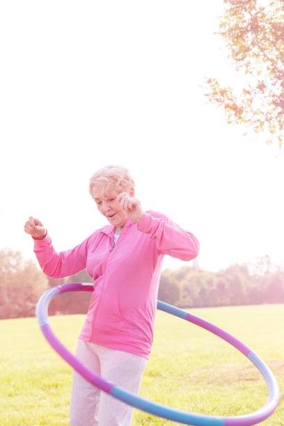 istock Active senior woman hula hooping in park 1158974361
