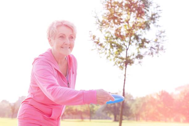 istock Healthy senior woman throwing disc in park 1158975805