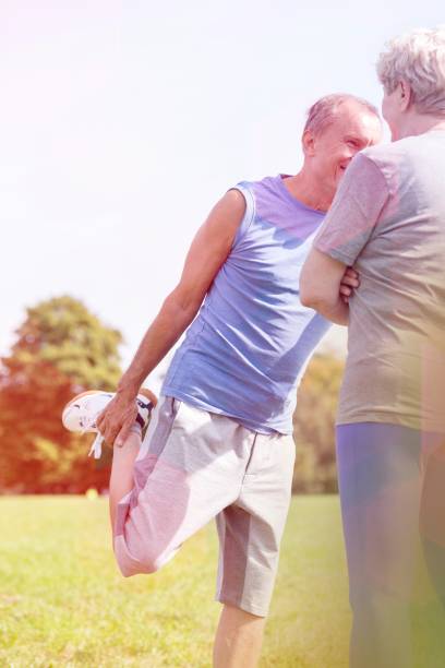 istock Senior man exercising while woman standing in park 1158975937