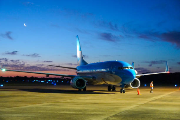 blue plane parking at the airport garage at the sunset with the moon