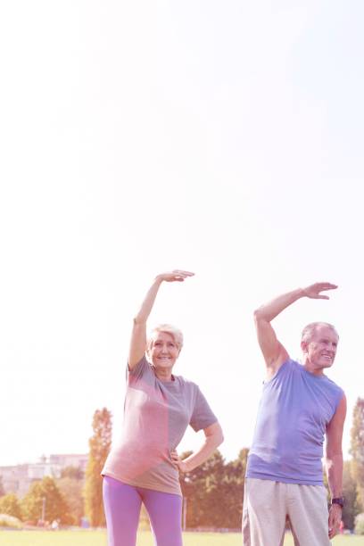 istock Senior couple doing stretching exercise in park against sky 1158976926