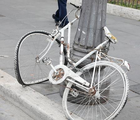 Abandoned bicycle hooked to pole missing its wheels