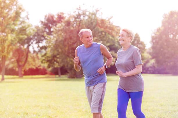 istock Healthy senior couple jogging in park 1158977677