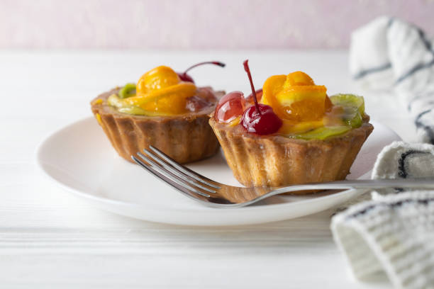 istock Mini fruit tarts with orange cherry and kiwi on white plate 1158978085