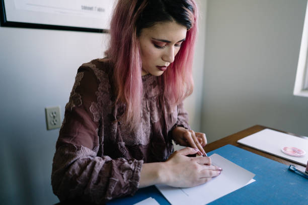 istock Girl with pink hair at home doing book binding 1158978954