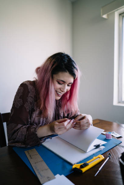 istock Girl with pink hair at home doing book binding 1158979165