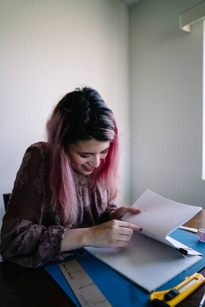istock Girl with pink hair at home doing book binding 1158979204