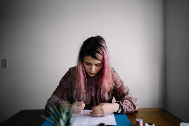 istock Girl with pink hair at home doing book binding 1158979809