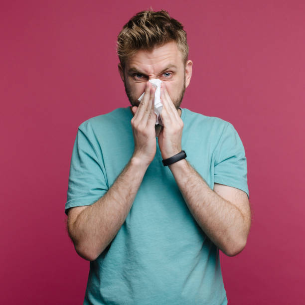 istock studio picture from a young man with handkerchief. Sick guy isolated has runny nose. man makes a cure for the common cold 1158990948