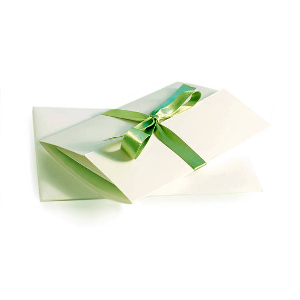 A white invitation folded and with a green ribbon