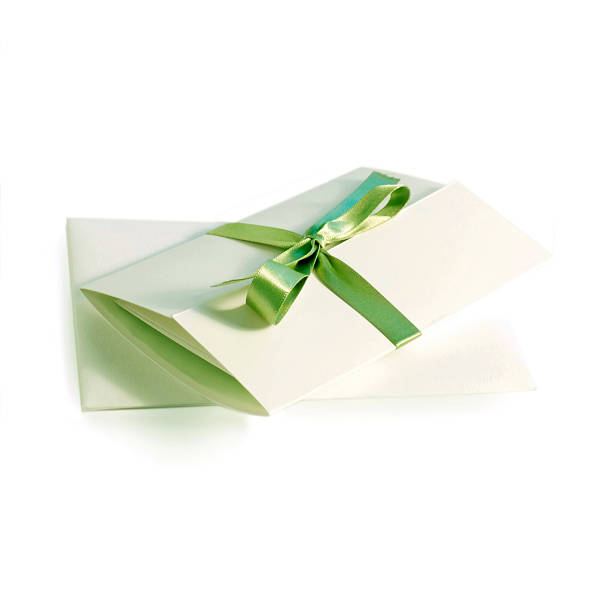 A white invitation folded and with a green ribbon stock photo