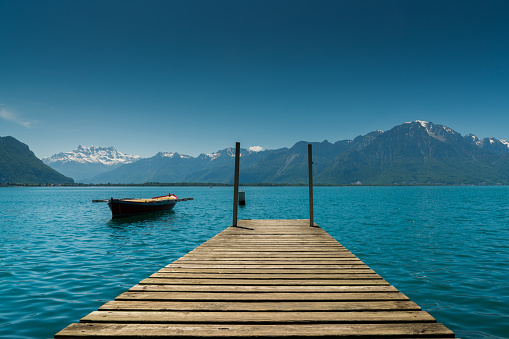 mountain and lake landscape with a vintage rescue rowboat and a wooden pier