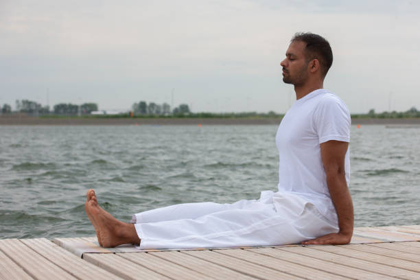 istock Man practice yoga on the beach at sunset 1159004339