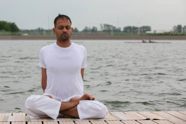 istock Young man doing yoga and meditating in warrior pose on beach 1159005287