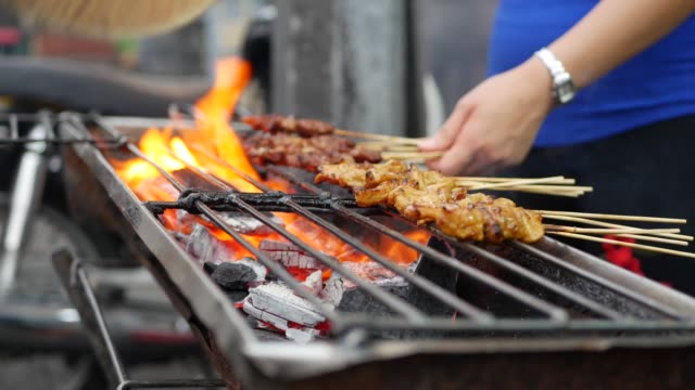 Traditional grilled meat on sticks cooked at street local market. Satay bbq. Closeup. 4k