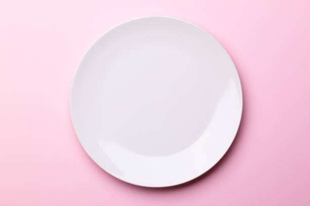 istock White isolated plate on a pink paper background. 1159009929