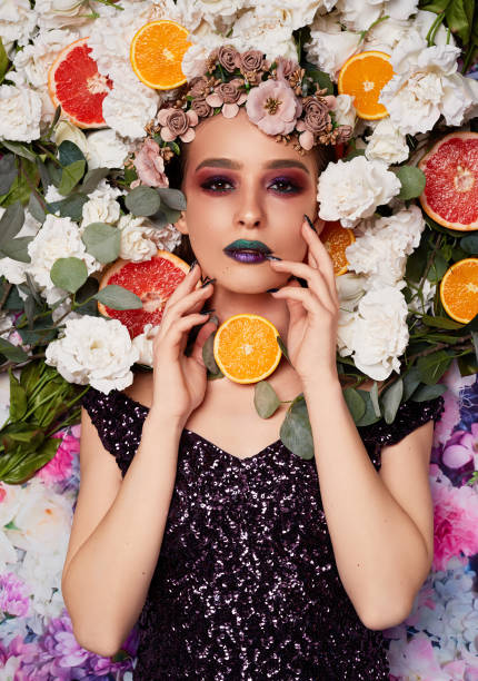 fashionable and cool high angle view of cool fashion model posing surrounded by fruits and flowers. floral crown photos stock pictures, royalty-free photos & images