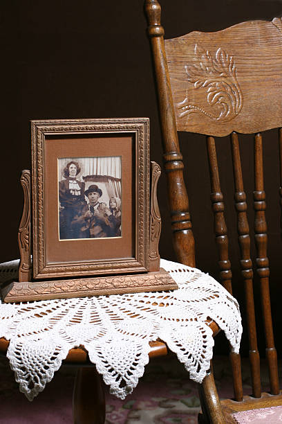Framed vintage photograph. Old-fashioned, retro, antique. Furniture. Sepia. Vintage photograph on a table covered with an antique crocheted scarf.  Carved ornate rocker sits crochet photos stock pictures, royalty-free photos & images