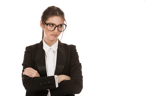 Closeup cutout portrait of a beautiful sad woman upset, annoyed jealous, envious or skeptical looking to the side, girl wearing black eyeglasses formal suit, shirt isolated on a pure white background