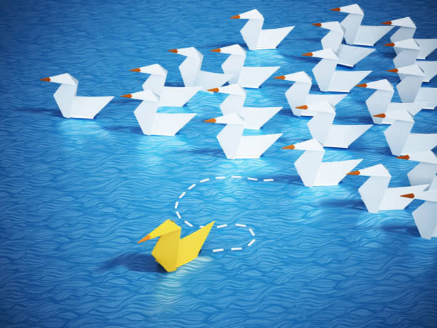 istock Yellow paper duck leaving the pack with white ducks. Conceptual image about standing out from the crowd 1159014884