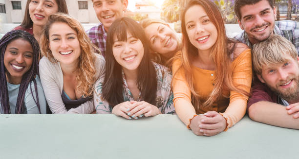 istock Happy millennial friends from diverse cultures and races having fun posing in front of smartphone camera - Youth and friendship concept - Young multiracial people smiling - Main focus on center faces 1159015512