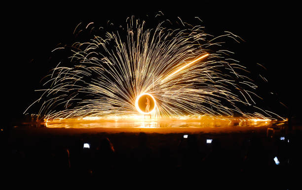 istock Spinning fire Show at night on the beach 1159016404