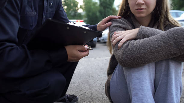 офицер пытается успокоить женщину-жертву автокатастрофы, шокированная девушка плачет - жертва стоковые фото и изображения